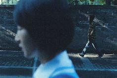 a man walking down a street next to a brick wall