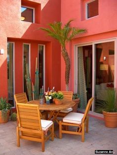 an outdoor dining table and chairs with potted plants in front of the patio doors