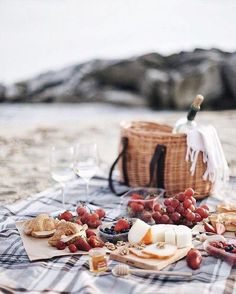 a picnic on the beach with grapes, cheese and bread