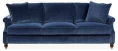 a blue velvet couch with four pillows on the armrests and one pillowed back