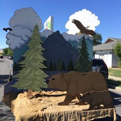 a bear and an eagle are on display in front of a mountain scene with trees