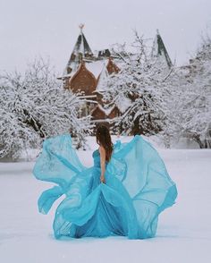 a woman in a blue dress walking through the snow