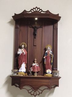 an ornate wooden clock with statues of mary, jesus and baby jesus on the shelf