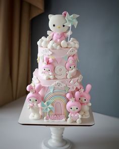 a hello kitty birthday cake with pink and white decorations on it's tiers