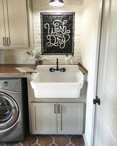 a washer and dryer in a small room next to a doorway with a chalkboard on the wall