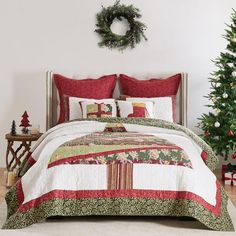 a bed with red and green quilts next to a christmas tree in a room