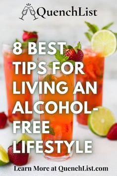 two glasses filled with alcohol and strawberries on top of a table next to limes