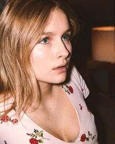 a close up of a person wearing a white shirt and red flowers on her top