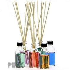 four bottles filled with different colored liquids and sticks