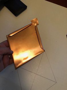 a person is cutting out a piece of gold paper