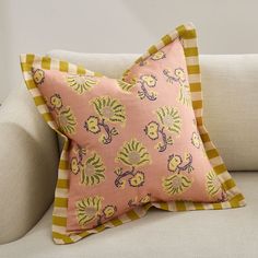 a pink and yellow pillow sitting on top of a white couch