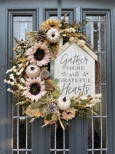 a wreath on the front door with sunflowers and pumpkins hanging from it