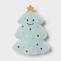 a blue christmas tree shaped pillow with a smiling face on it's side and confetti sprinkles all around the edges