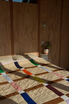 the bed is made up with multicolored quilts on it's sides