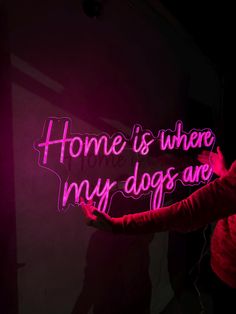 a woman holding up a neon sign that says home is where my dogs and cats are