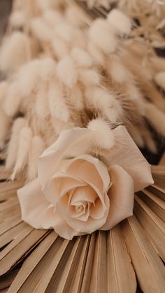 a white rose laying on top of a bed next to fluffy fur covered bedspreads