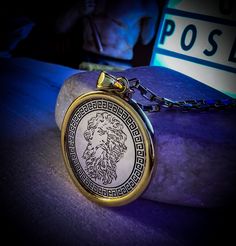 a close up of a pocket watch on a rock with a sign in the background