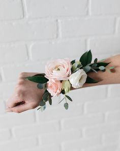 a woman's arm with flowers and greenery on it, in front of a brick wall