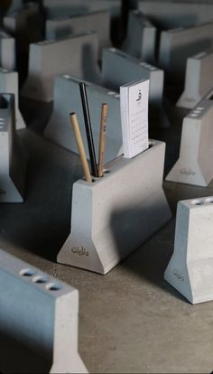 there are many concrete blocks with pens and pencils in them on the table next to each other