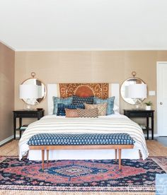 a bedroom with a bed, mirror and rug on the floor