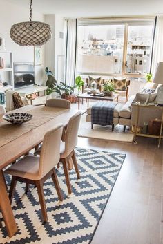 a dining room table with chairs and a rug in front of the window that overlooks a cityscape