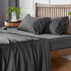 a bed with blue sheets and pillows on top of it next to a wooden headboard