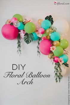 some balloons and flowers are hanging on the wall in front of a white wall with green leaves