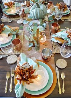 the table is set with plates, silverware and pumpkins