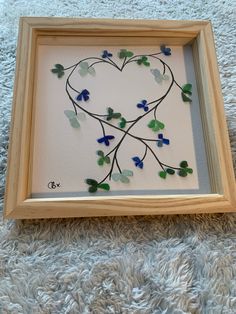 a heart made out of glass sitting on top of a white rug next to a wooden frame