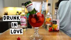 a drink in a glass with strawberries on the table next to bottles and glasses