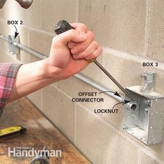 a man is working on the side of a wall with tools and screwdrivers