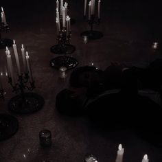 a person laying on the ground surrounded by many lit candles in black and white colors