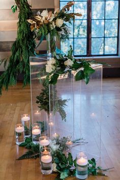 an arrangement of candles and greenery on the floor