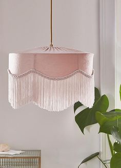 a pink chandelier hanging from a ceiling in a room with white walls and plants