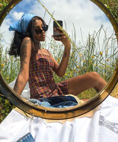 a woman taking a selfie with her cell phone while sitting in front of a mirror