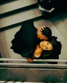 a man and woman standing next to each other on top of a stair case together