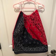 a red and black bandana hanging on a white door with a metal hook in front of it