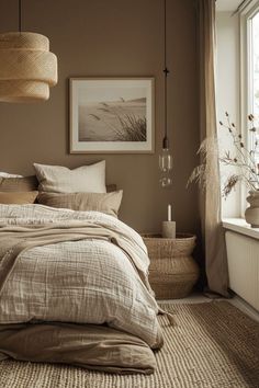 a bed sitting next to a window in a bedroom under a light brown blanket and pillows