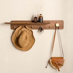 a hat and purse are hanging on a wooden shelf next to a wall mounted coat rack