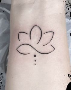 a black and white photo of a lotus tattoo on the wrist, with dots in it