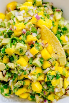 a white bowl filled with fruit and veggies next to a tortilla