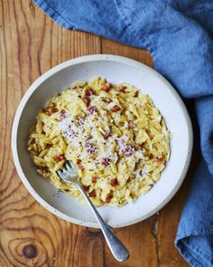 a white bowl filled with pasta on top of a wooden table