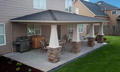 a covered patio with chairs and grill in the back yard