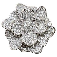 a flower shaped brooch with white diamonds in the center, on a white background