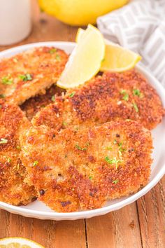 two crab cakes on a white plate with lemon wedges and a glass of milk