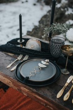 a table set with black plates and silverware