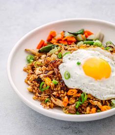 a white bowl filled with rice, vegetables and an egg