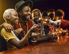 a group of people sitting at a bar with drinks in their hands and one person handing something to the other