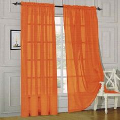 an orange curtain hanging on the side of a white wall next to a wooden floor