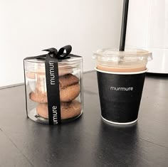 a cup of coffee sitting next to a container of doughnuts on a table